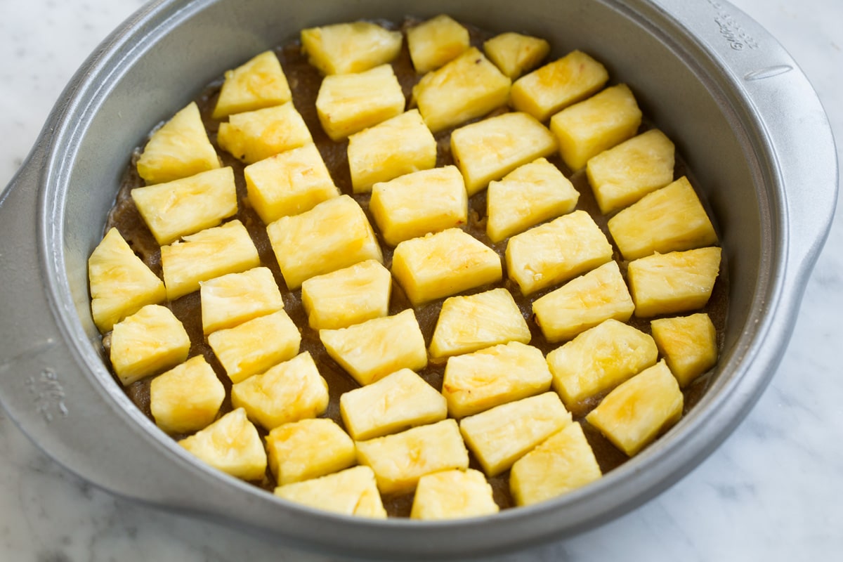 Pineapple Upside Down Cake Adding fresh pineapple chunks over brown sugar layer in cake pan.