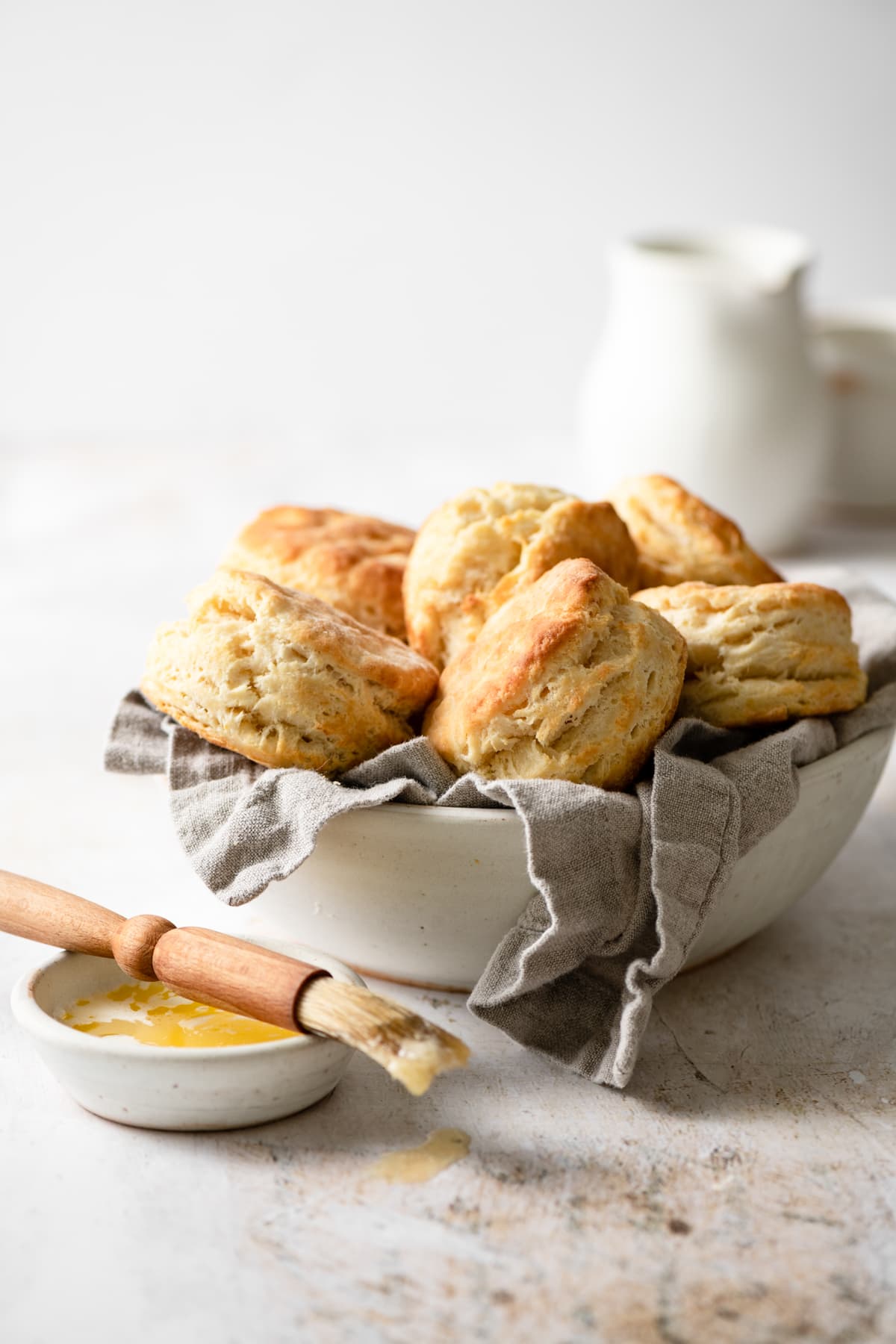 Best Homemade Biscuits Bowl full of buttermilk biscuits with a pastry brush and butter on the side.