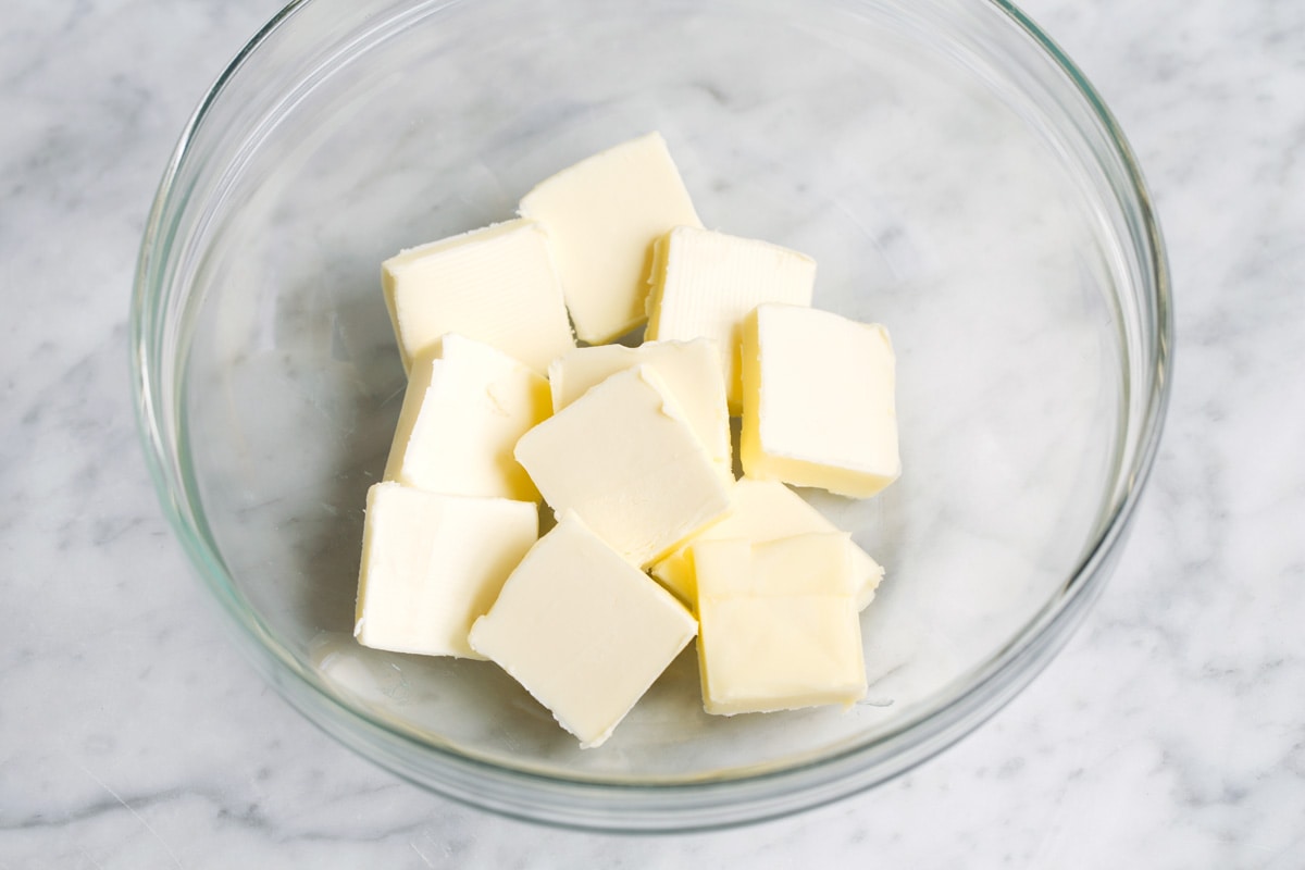 Best Cocoa Brownies Showing how to make brownies. Adding sliced cubes of butter in glass mixing bowl.