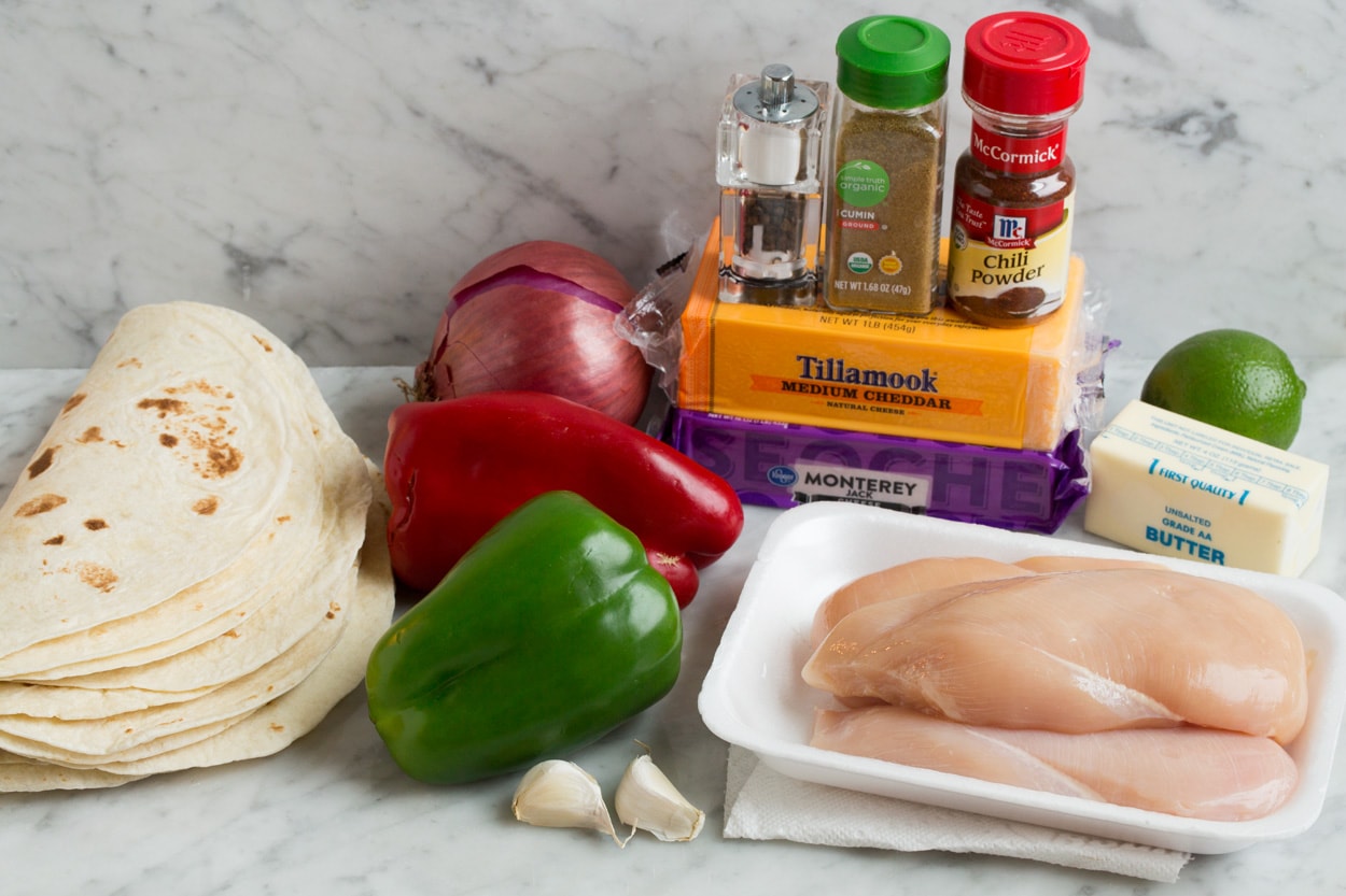 Loaded Chicken Quesadillas Quesadilla ingredients shown here including tortillas, butter, cheese, chicken, bell peppers, red onion, garlic, cumin, chili powder and lime.