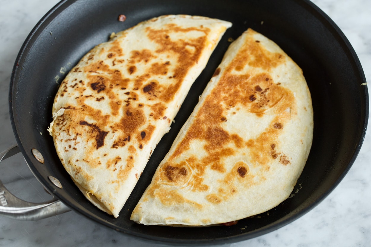 Loaded Quesadillas Two quesadillas in a skillet shown after cooking with golden brown exterior.