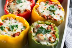 Multi-color stuffed peppers in a white baking dish.