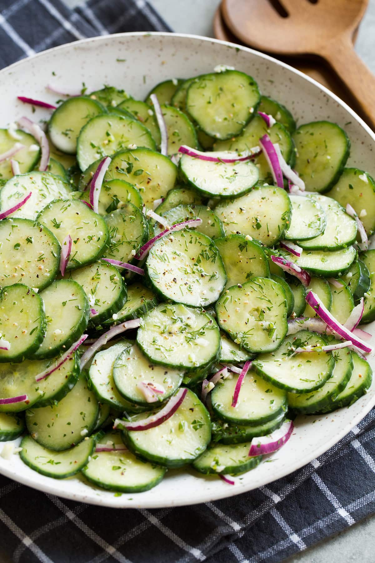 Cucumber Salad Cucumber salad shown in white ceramic serving bowl set over a dark grey napkin.