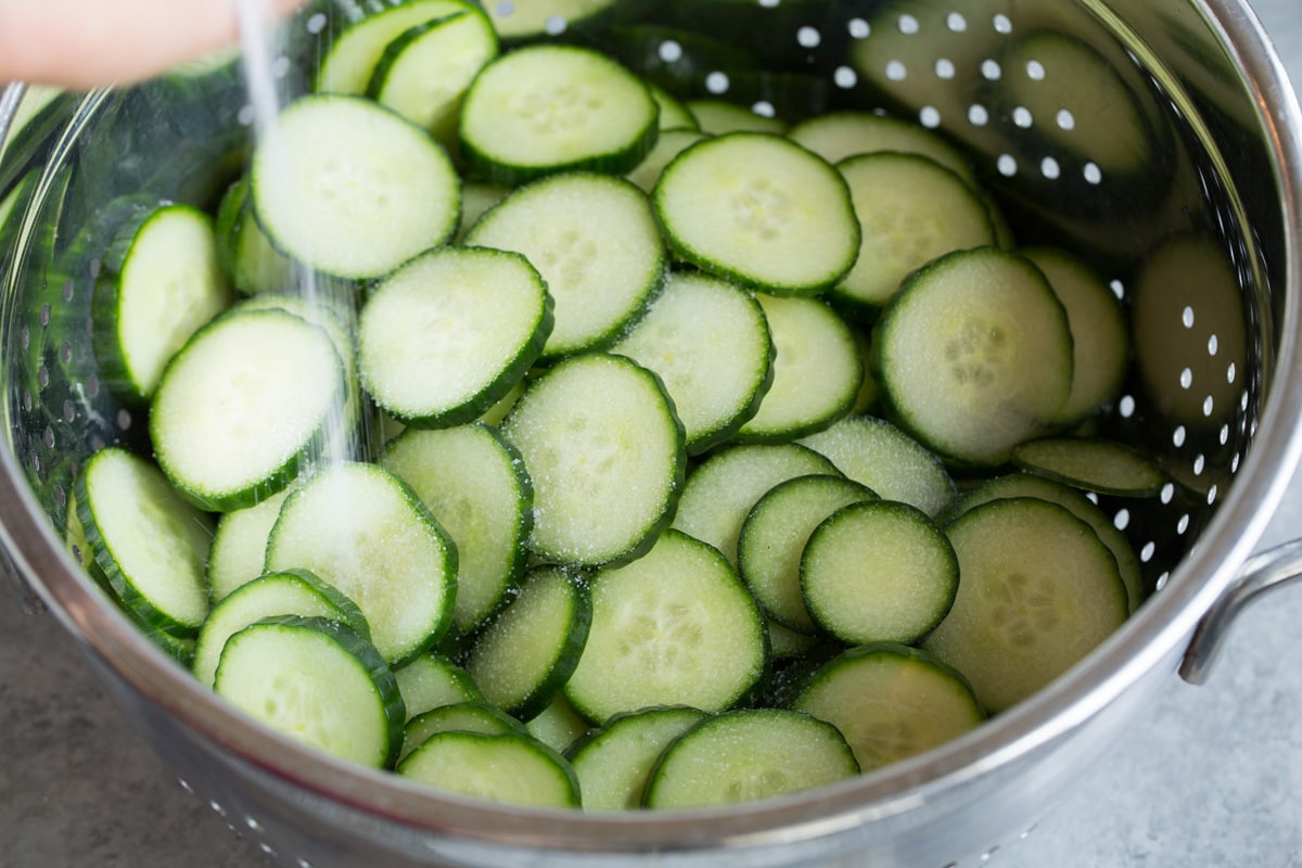 Refreshing Cucumber Salad Showing how to make cucumber salad. Tossing cucumbers in a colander with salt.