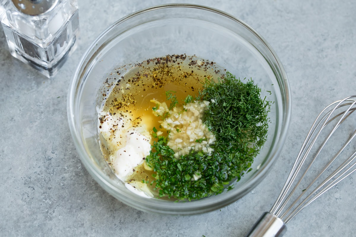 Refreshing Cucumber Salad Making cucumber salad dressing. Whisking apple cider vinegar, mayonnaise, honey, olive oil, dill, parsley, garlic, salt and pepper,