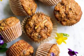 Overhead image of morning glory muffins on a marble surface decorated with spring flowers.