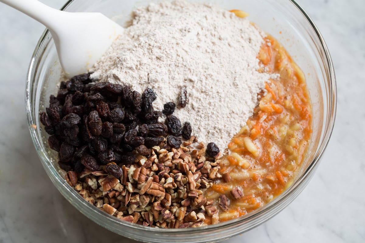 Morning Glory Muffins Adding flour mixture to wet mixture along with raisins and pecans. Folding with a rubber spatula to incorporate.