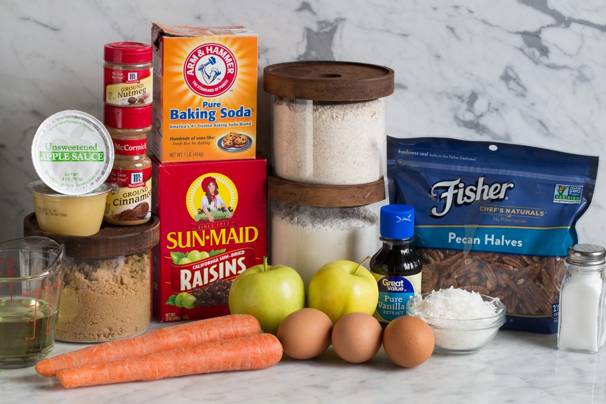 Morning Glory Muffins Ingredients needed for morning glory muffins shown here including wheat flour, white flour, baking soda, cinnamon, nutmeg, salt, brown sugar, apples carrots, raisins, coconut, eggs, vegetable oil, vanilla, pecans and applesauce.