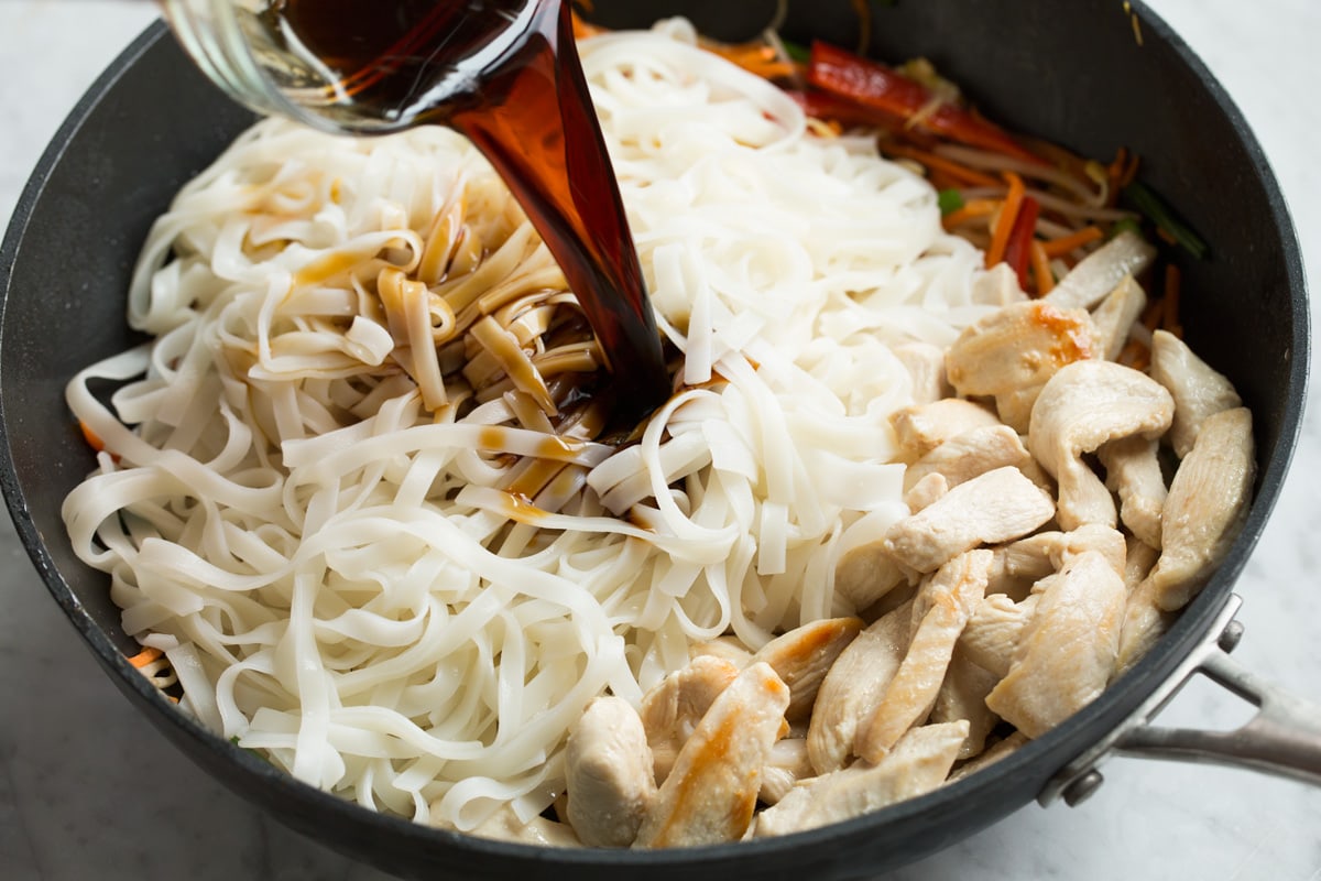 Pad Thai (with Chicken or Shrimp) Adding rice noodles, cooked chicken and sauce to finish Pad Thai in wok.