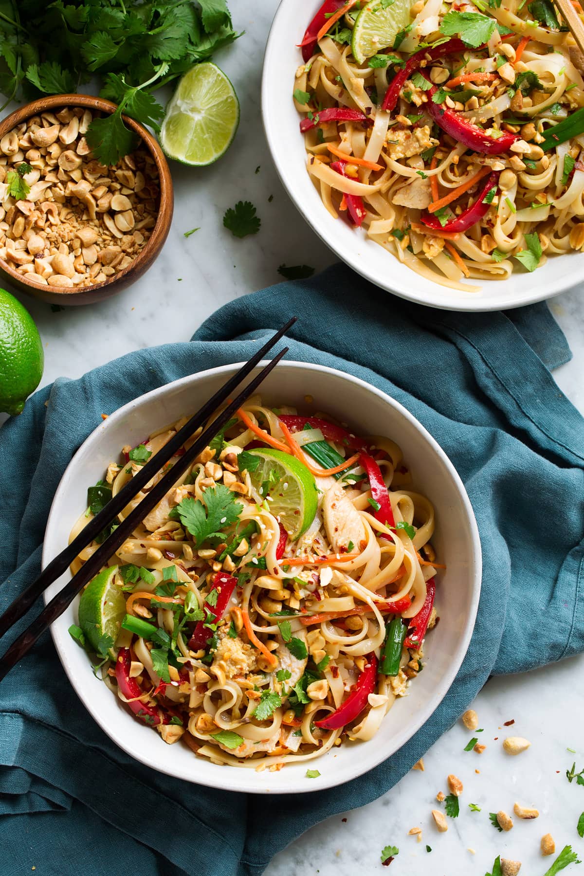 Pad Thai with Chicken or Shrimp Two servings of pad thai in white bowls, with chopsticks on the side, set over a blue napkin.