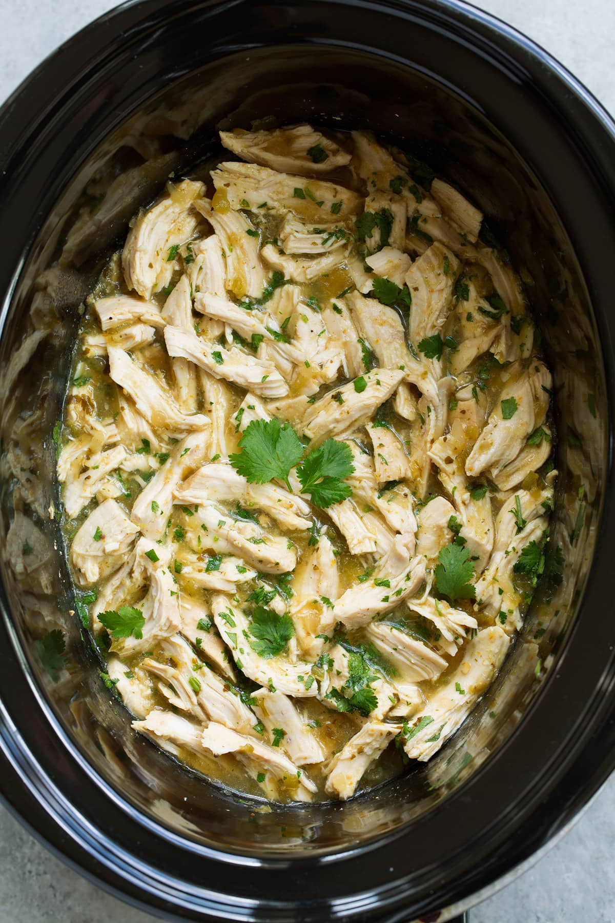 Salsa Verde Chicken Tacos (Slow Cooker or Instant Pot) Overhead image of salsa verde chicken in a black crockpot.