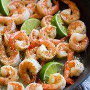 Close up image of shrimp with honey lime sauce in a black skillet.