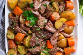 Slow Cooker Pot Roast with potatoes and carrots on a white oval serving platter set over marble.