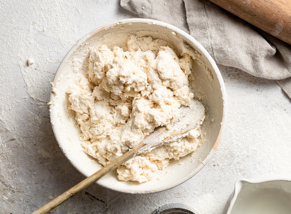 Homemade Buttermilk Biscuits Mixing buttermilk into biscuit dough in a mixing bowl.