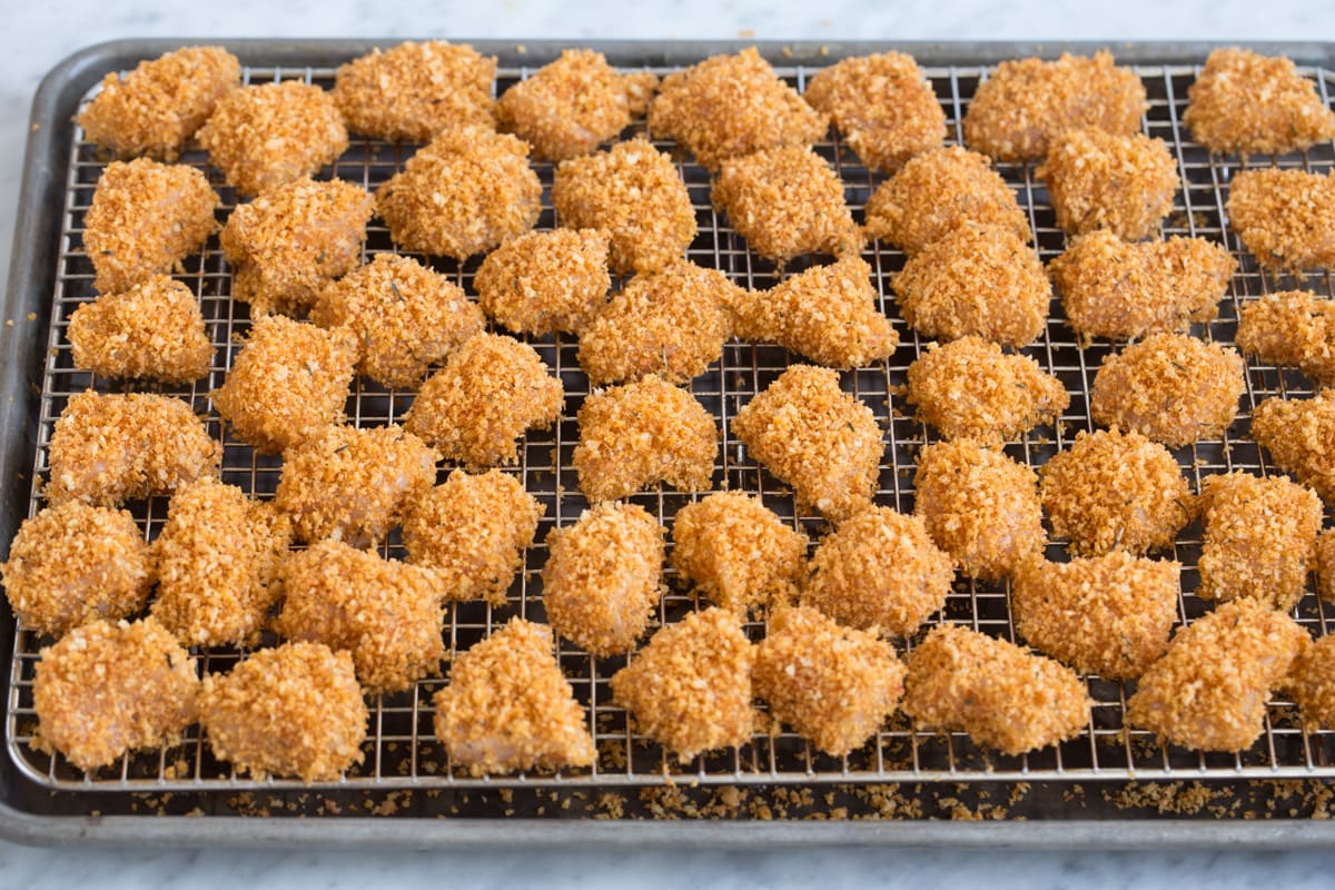 Baked Chicken Nuggets Showing how chicken nuggets look on wire rack over baking sheet before baking.