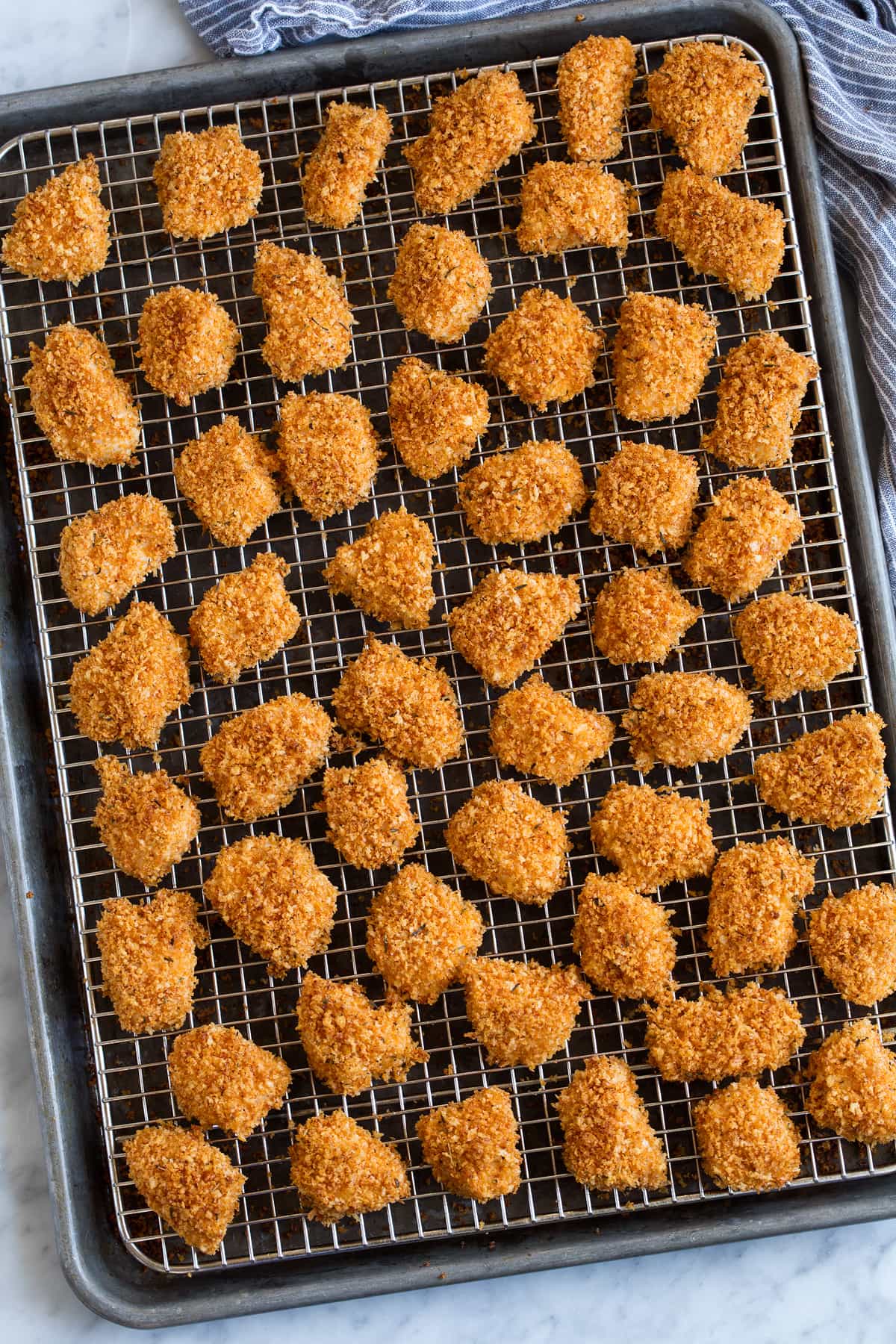Baked Chicken Nuggets Chicken Nuggets shown on wire rack over baking sheet after baking.