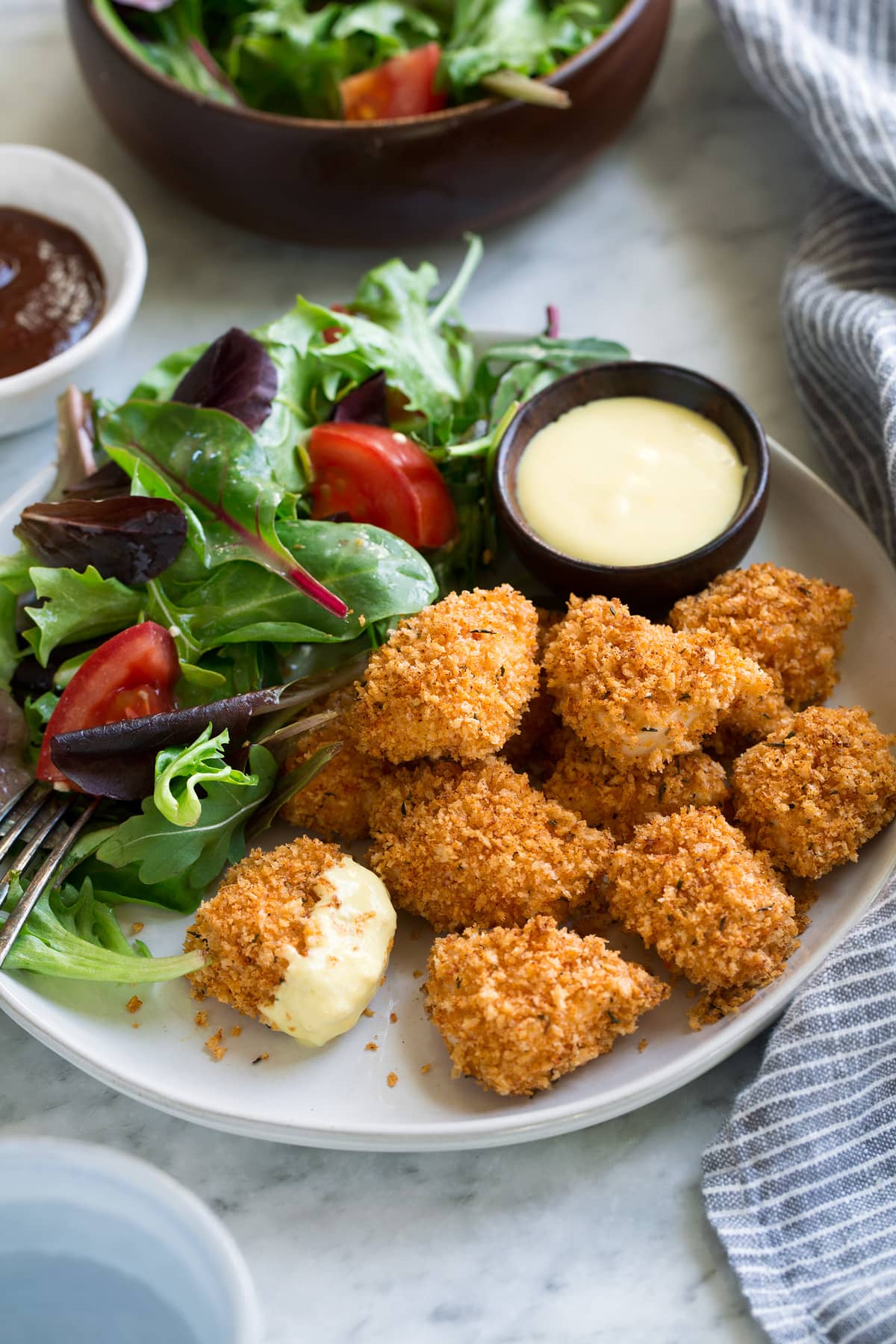Crispy Baked Chicken Nuggets Chicken Nuggets on a serving plate with a side salad.