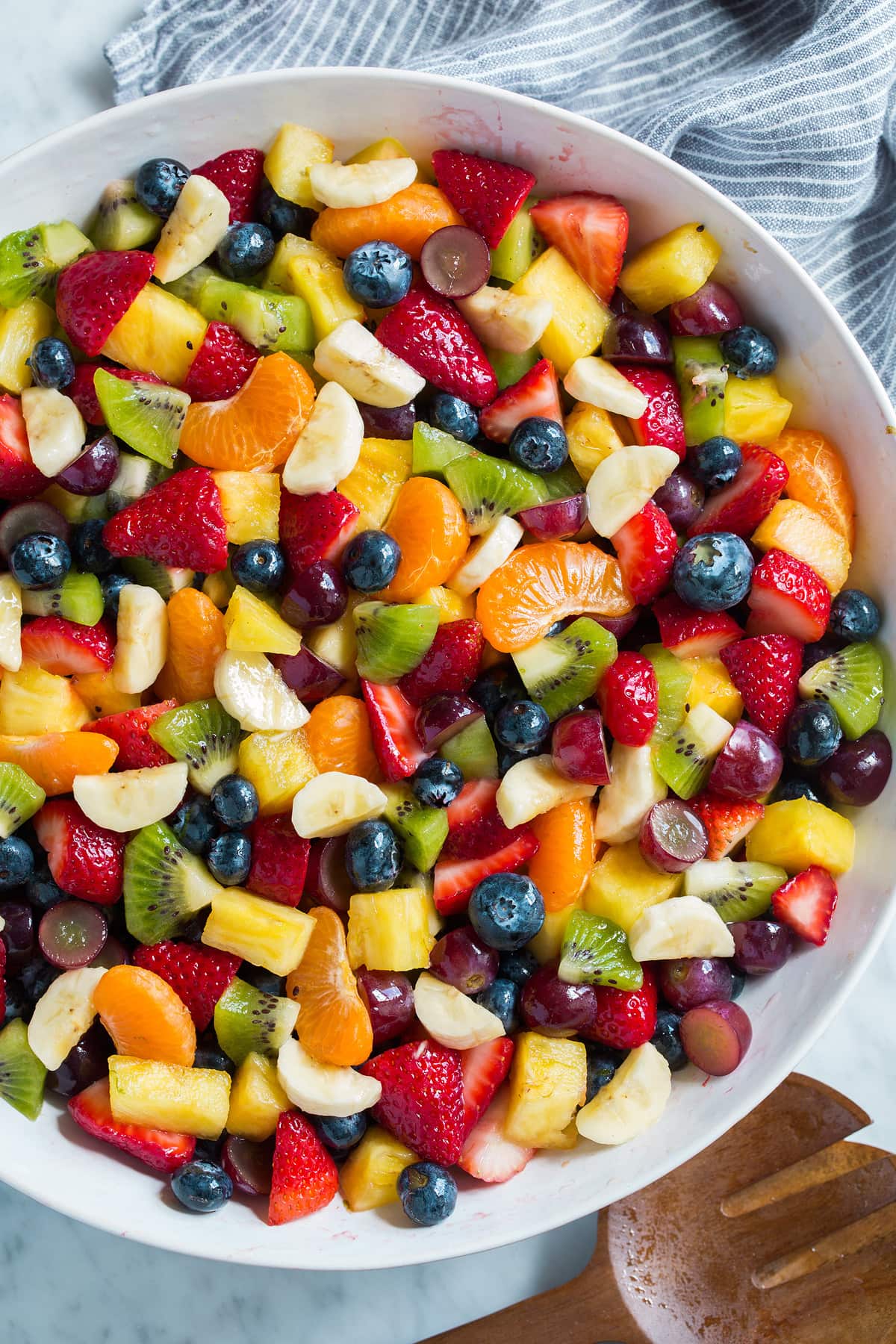 Rainbow Fruit Salad with Honey Lime Dressing Fruit Salad with rainbow of colors in a large white serving bowl.