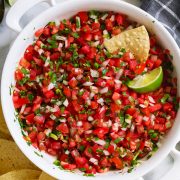 Overhead image of homemade pico de gallo in a white serving bowl with a side of tortilla chips.
