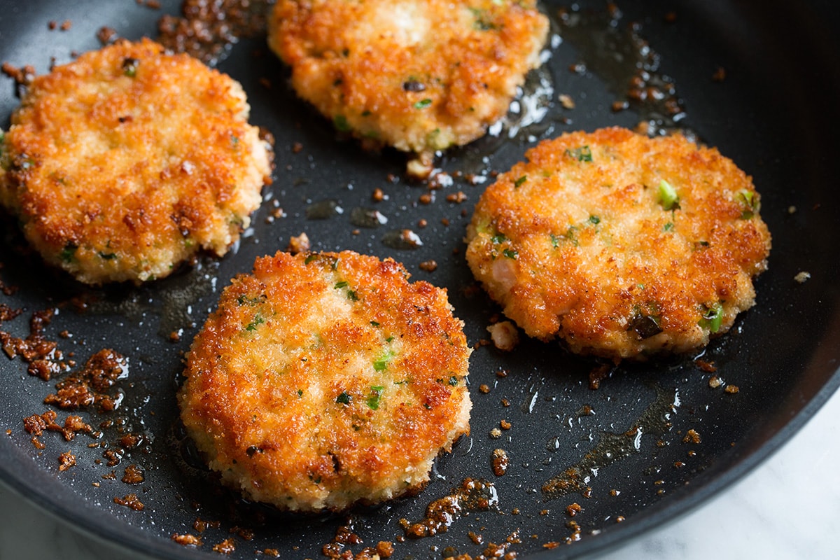 Crispy Salmon Patties (made with fresh salmon, not canned!) Salmon patties frying in oil in a skillet.