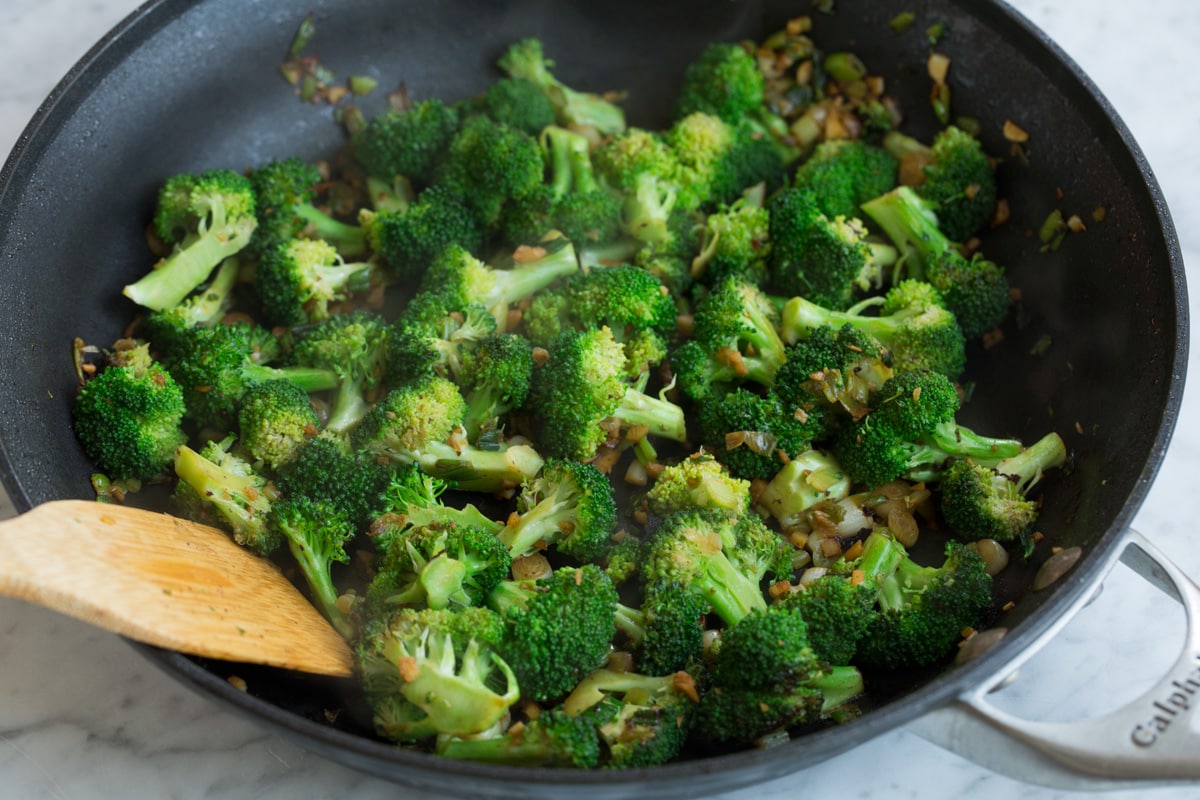 Beef and Broccoli - this is a staple dinner recipe! Easy, flavorful and sure to satisfy! #beef #broccoli #chinese #recipe Cooking broccoli, onions and garlic in a skillet to make beef and broccoli.