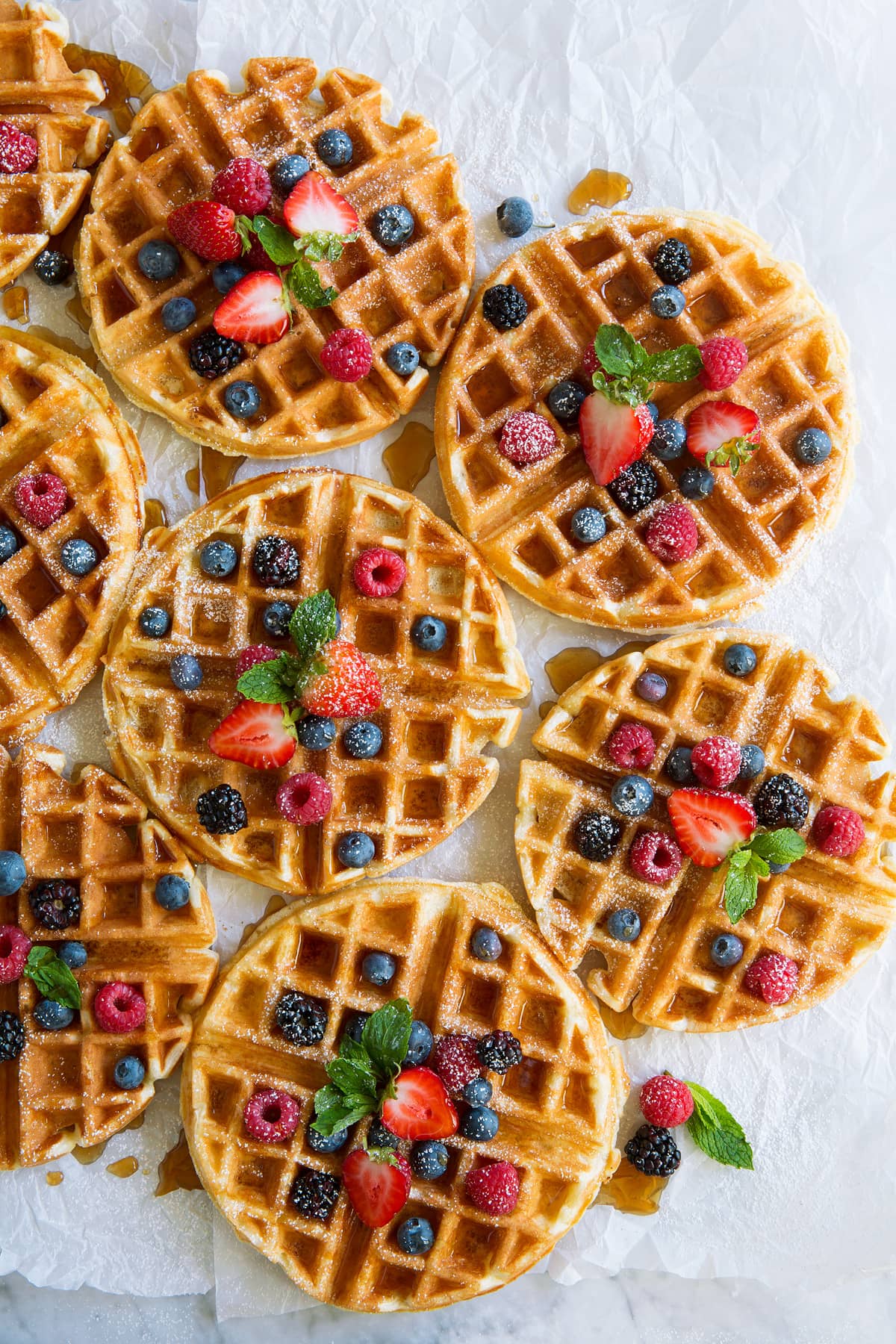 Belgian Waffles - these turn out perfect every time! Light, fluffy and tender on the inside and crisp and golden on the outside. A family favorite recipe! #belgian #waffles #breakfast Eight Belgian Waffles topped with berries and maple syrup.