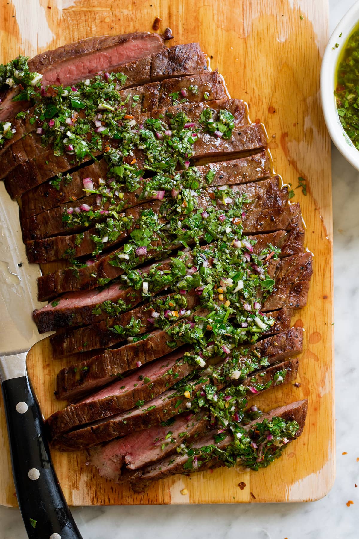 Chimichurri Recipe Showing a serving suggestion for homemade chimichurri, serving it over sliced steak.