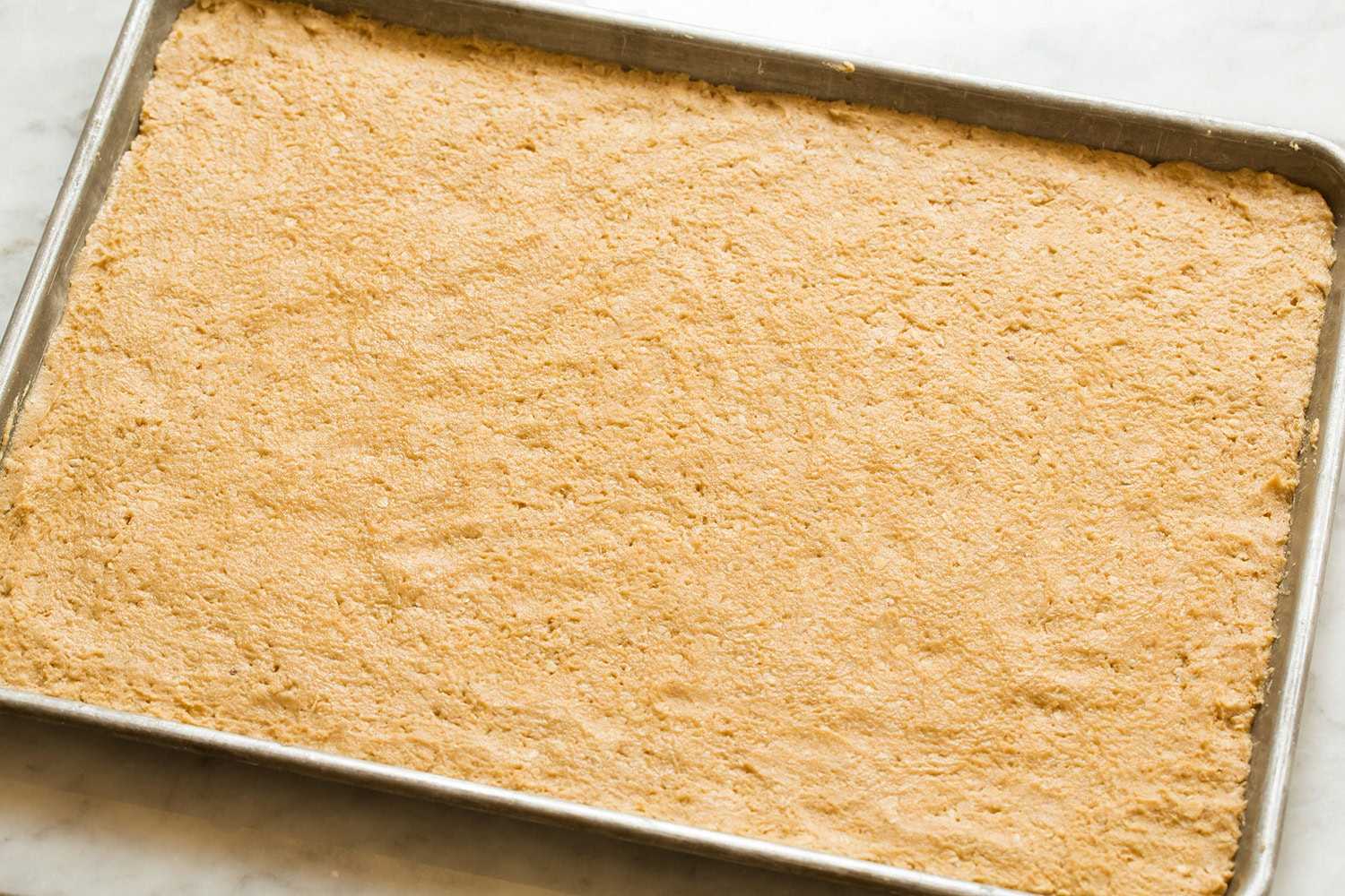 Peanut Butter Bars Peanut butter cookie dough spread onto baking sheet evenly.