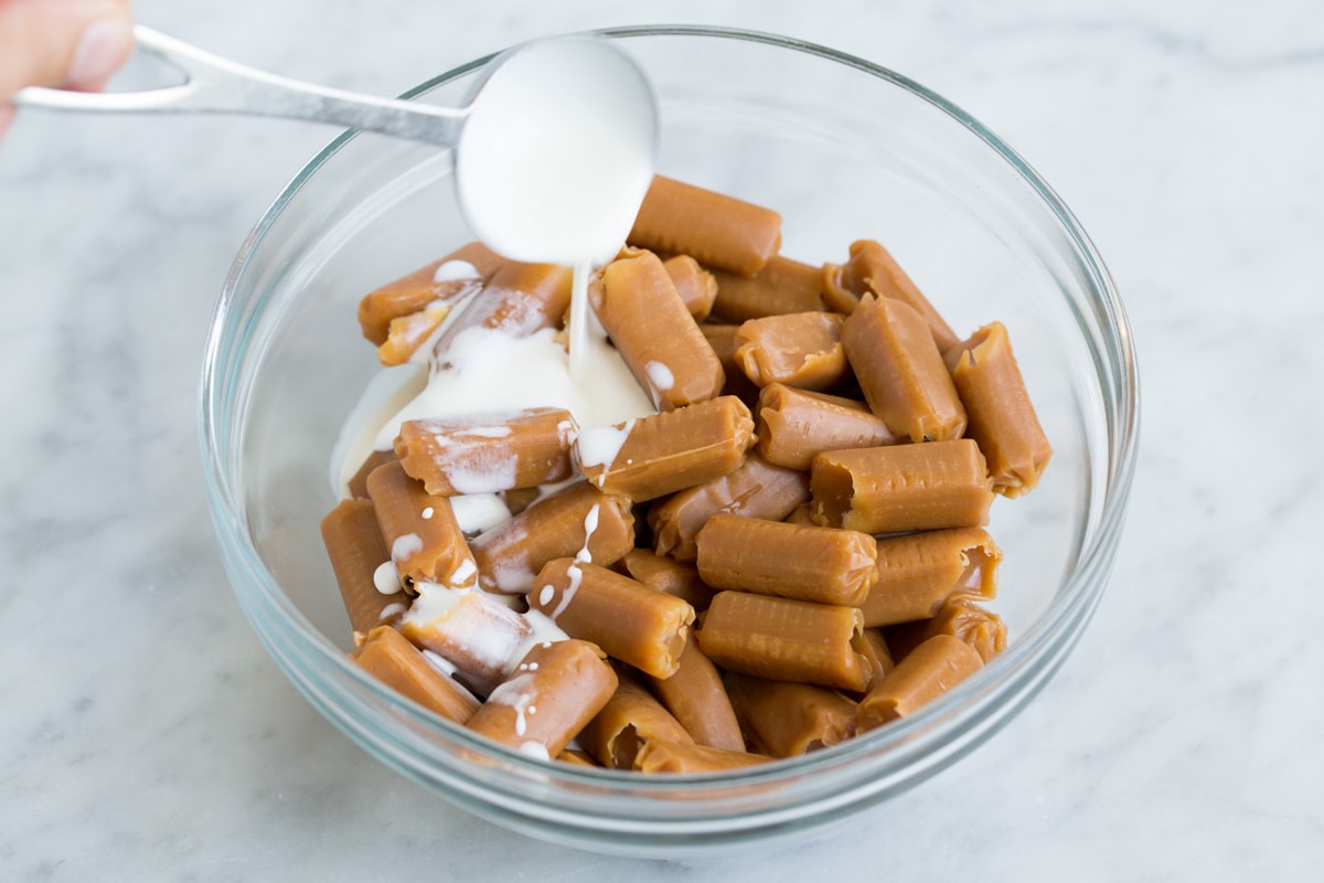 adding cream to caramels in glass bowl