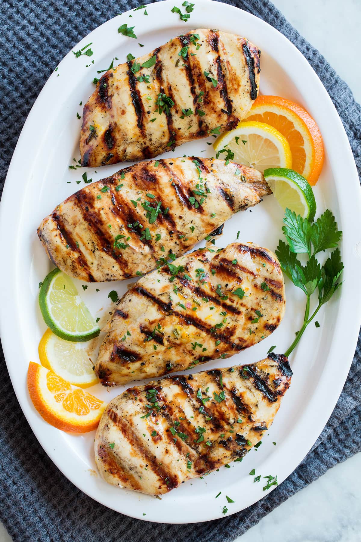 Triple Citrus Chicken Marinade - perfectly bright and refreshing! Total upgrade to plan chicken breasts or thighs. Such a delicious summer recipe! #chicken #marinade #recipe #dinner #grilled Overhead image of chicken breasts coated with marinade on a serving platter.