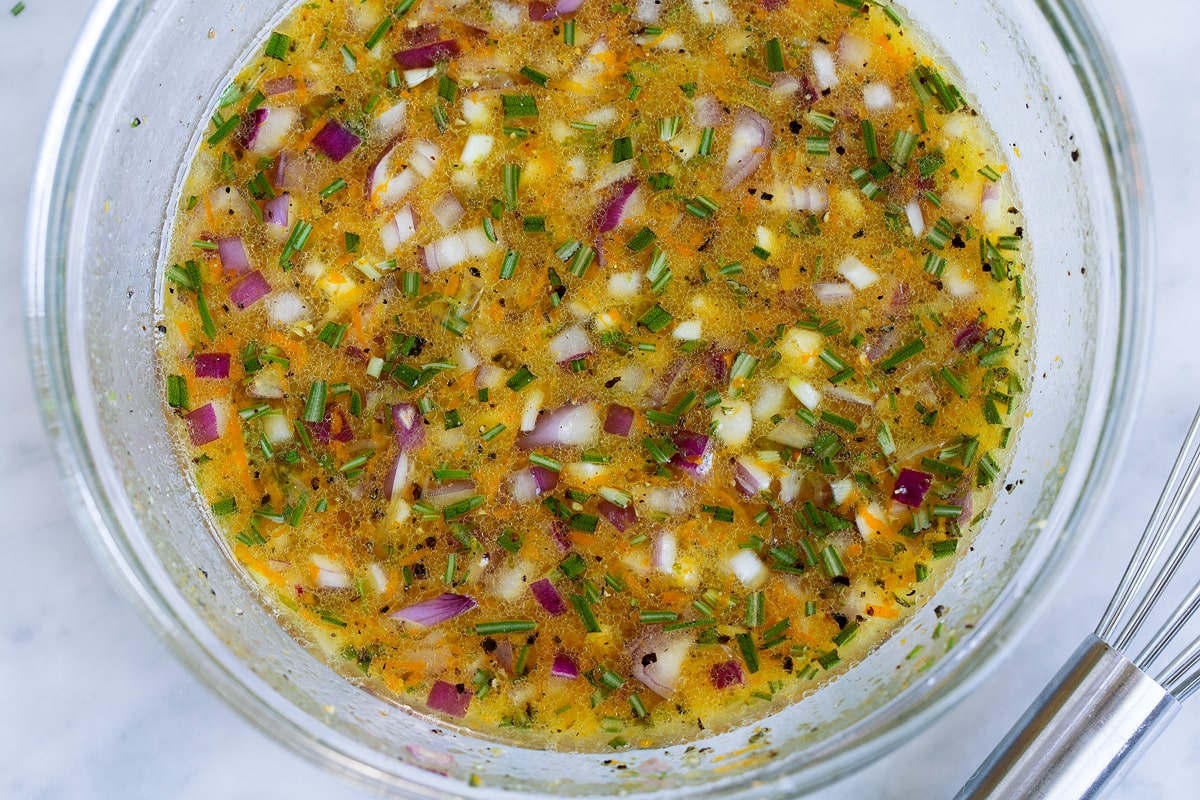 Triple Citrus Chicken Marinade - perfectly bright and refreshing! Total upgrade to plan chicken breasts or thighs. Such a delicious summer recipe! #chicken #marinade #recipe #dinner #grilled Chicken marinade in a glass mixing bowl. Made with citrus, olive oil, herbs, garlic and red onion.