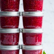Raspberry jam in small glass mason jars.