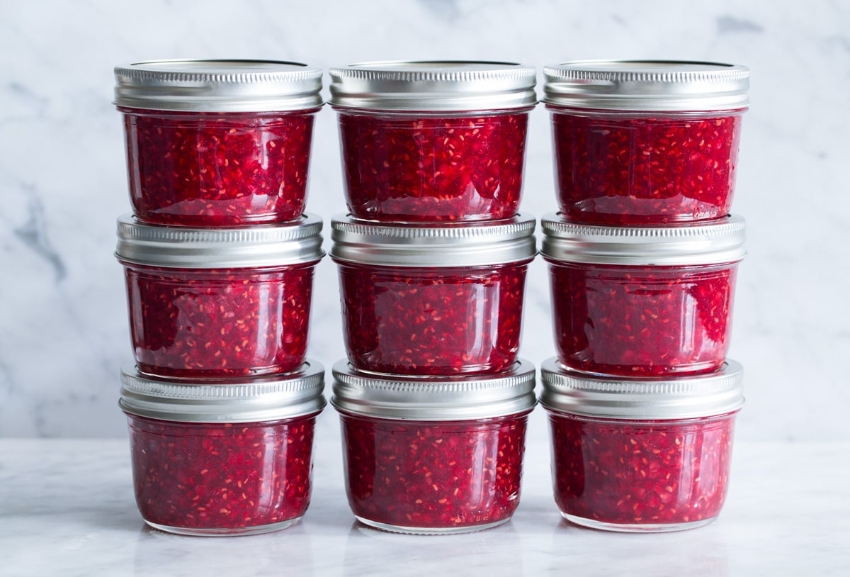 Easy Homemade Raspberry Freezer Jam - no canning skills or equipment required! This is my all time favorite jam! I've been making it for 10+years, it's the only jam I make now. Everyone always loves it and it freezes for up to 1 year! #jam #freezerjam #homeamdejam #easyrecipe Stacks of homemade raspberry freezer jam.