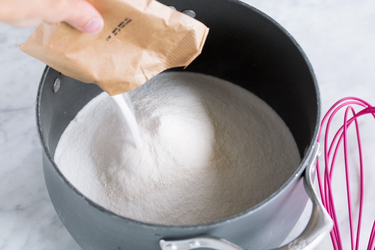 Easy Homemade Raspberry Freezer Jam - no canning skills or equipment required! This is my all time favorite jam! I've been making it for 10+years, it's the only jam I make now. Everyone always loves it and it freezes for up to 1 year! #jam #freezerjam #homeamdejam #easyrecipe Adding pectin to sugar in pot.