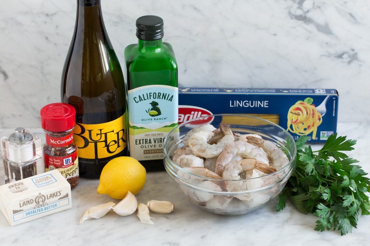 Shrimp Scampi - shrimp are seared in an incredibly flavorful buttery wine sauce and tossed with pasta for the perfect, unforgettable dinner! Everyone will go crazy over this! #shrimp #scampi #pasta #garlic #dinner #recipe Shrimp scampi ingredients shown here including shrimp, wine, lemon, garlic, butter, olive oil, shrimp, parsley, red pepper flakes, salt and pepper, and pasta.