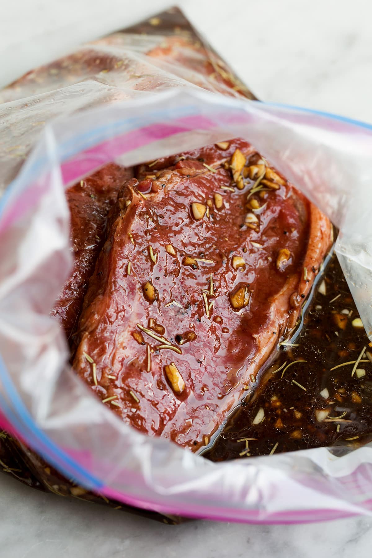 The BEST Steak Marinade! Made with balsamic vinegar and a handful of other pantry staples. A summer must have recipe! #steak #marinade Steak soaking in a steak marinade.