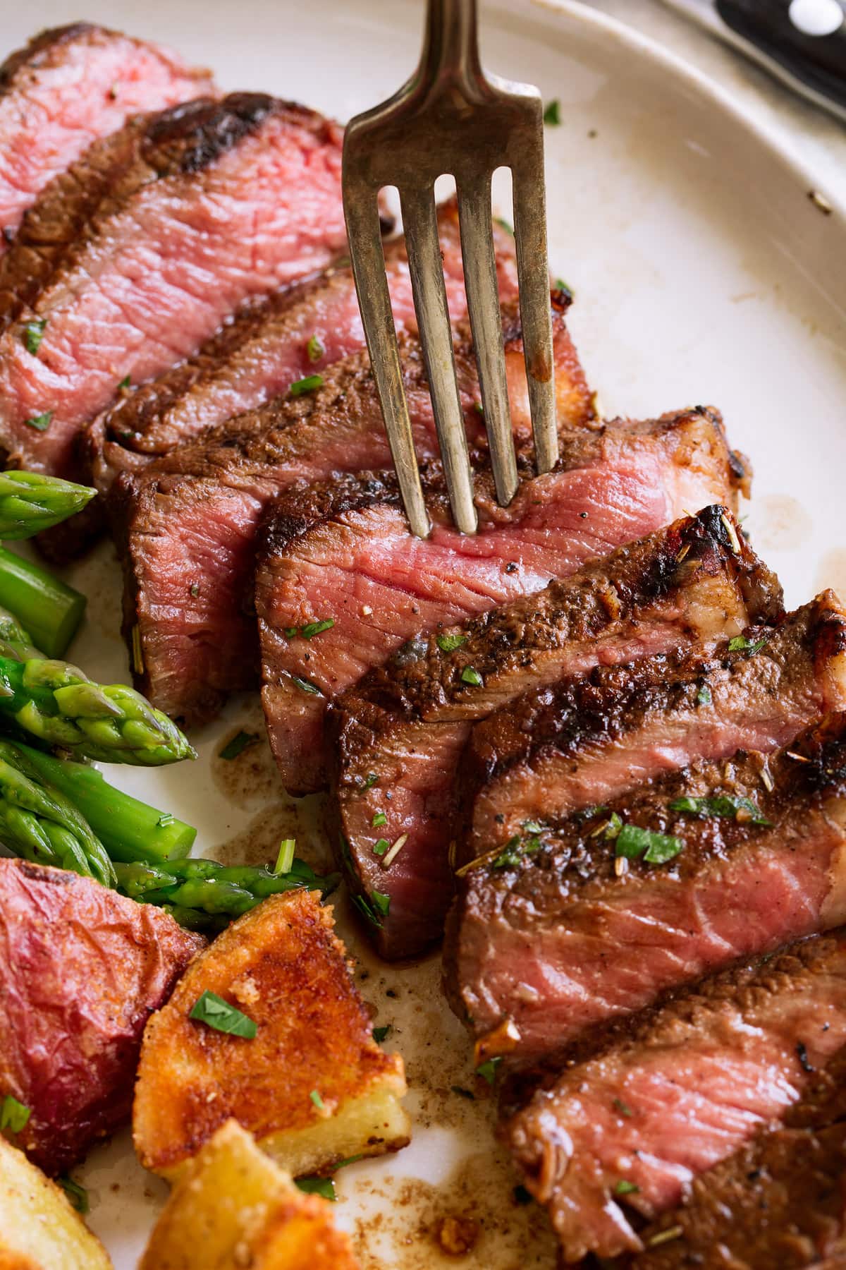 The Ultimate Steak Marinade! Close up image of sliced marinated steak with fork.