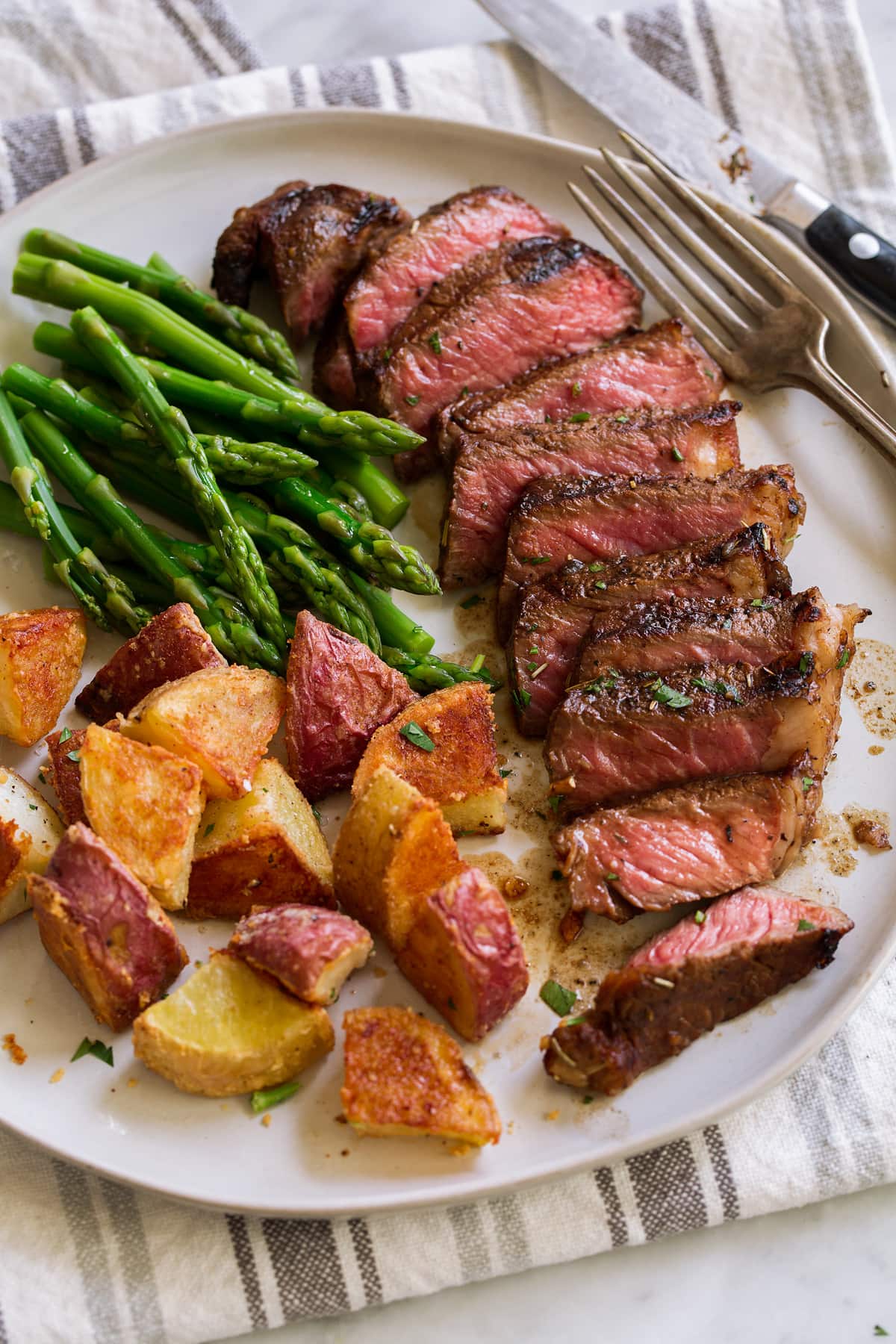 The BEST Steak Marinade! Made with balsamic vinegar and a handful of other pantry staples. A summer must have recipe! #steak #marinade Serving of sliced steak with steak marinade.