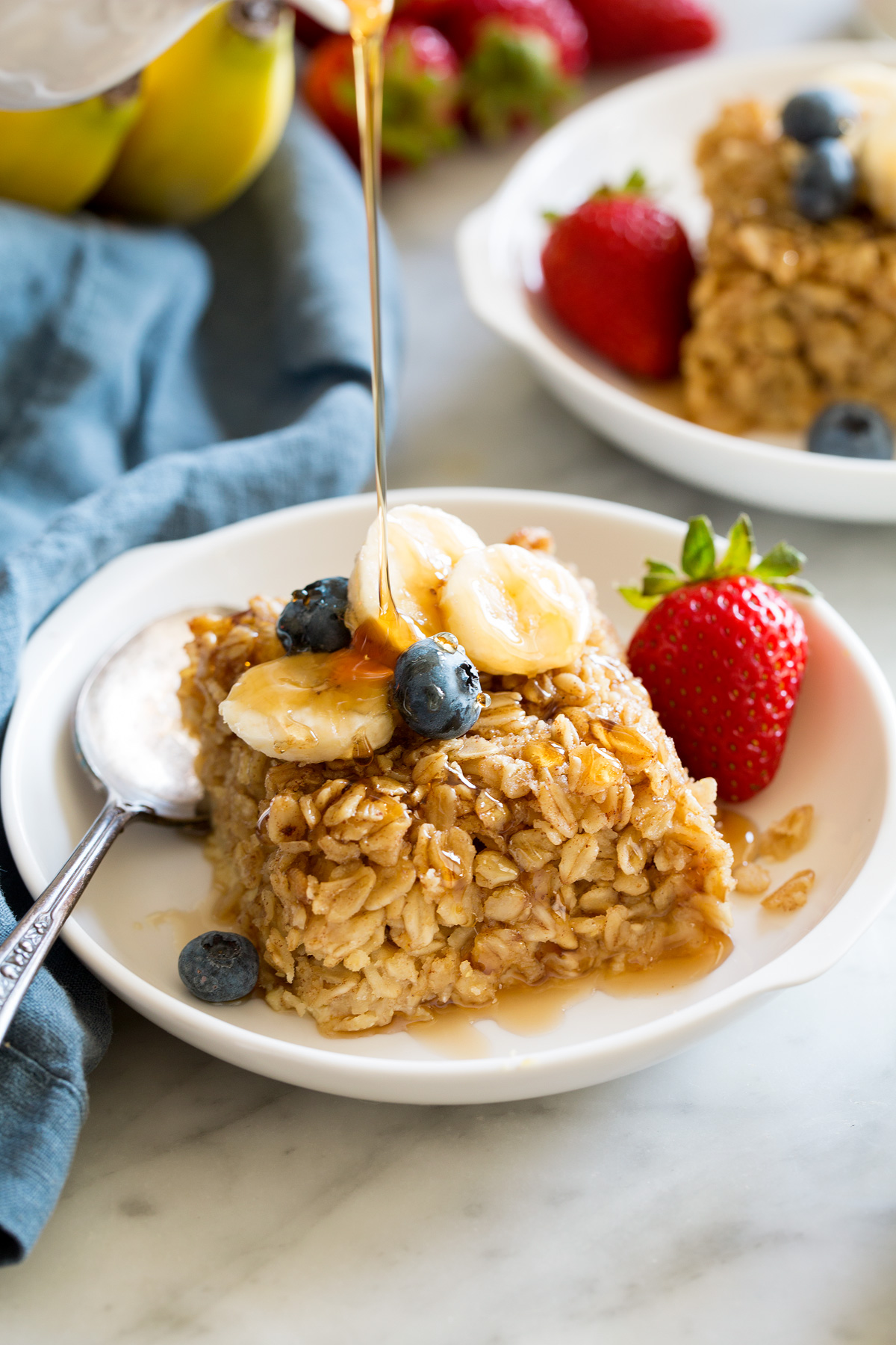 Slice of baked oatmeal topped with fresh fruit and maple syrup.