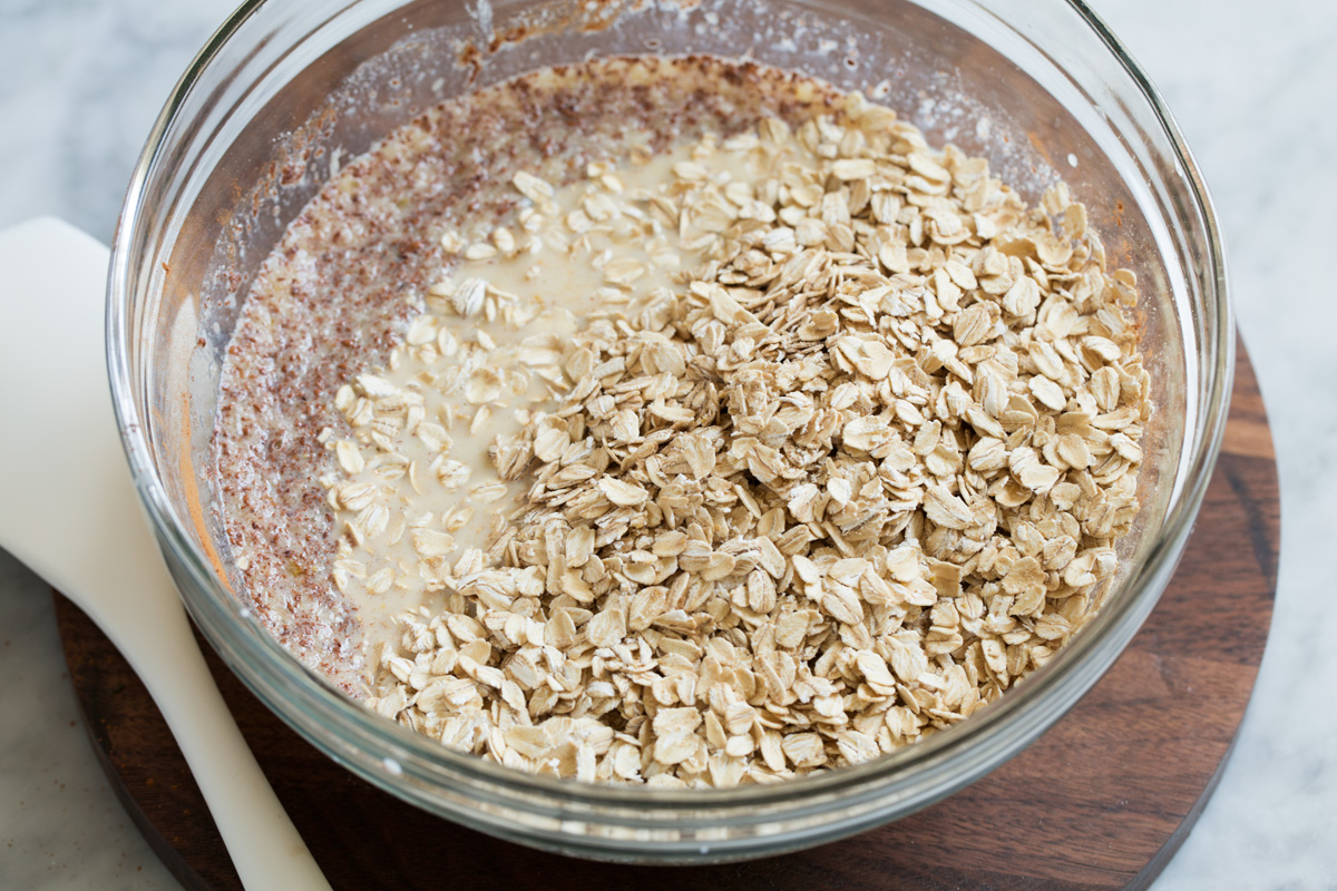 Baked Oatmeal Mixing oats into liquid mixture in glass mixing bowl.