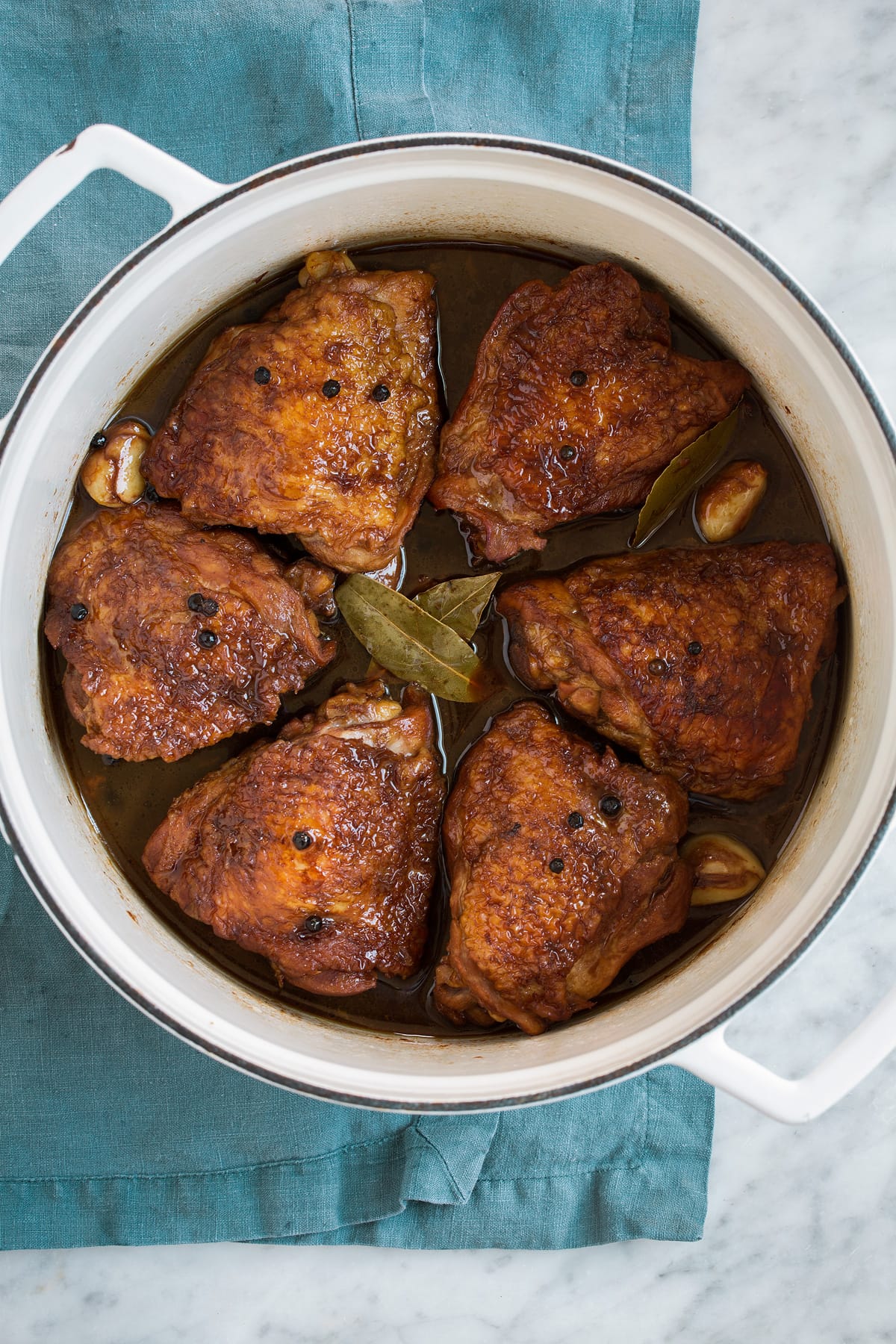 Chicken Adobo - easy Filipino chicken recipe made with soy sauce, vinegar, garlic and a hint of brown sugar. Tastes similar to teriyaki sauce but not quite so sweet. A perfect weeknight dinner! #chicken #adobo #recipe Overhead image of chicken adobo in a white pot.