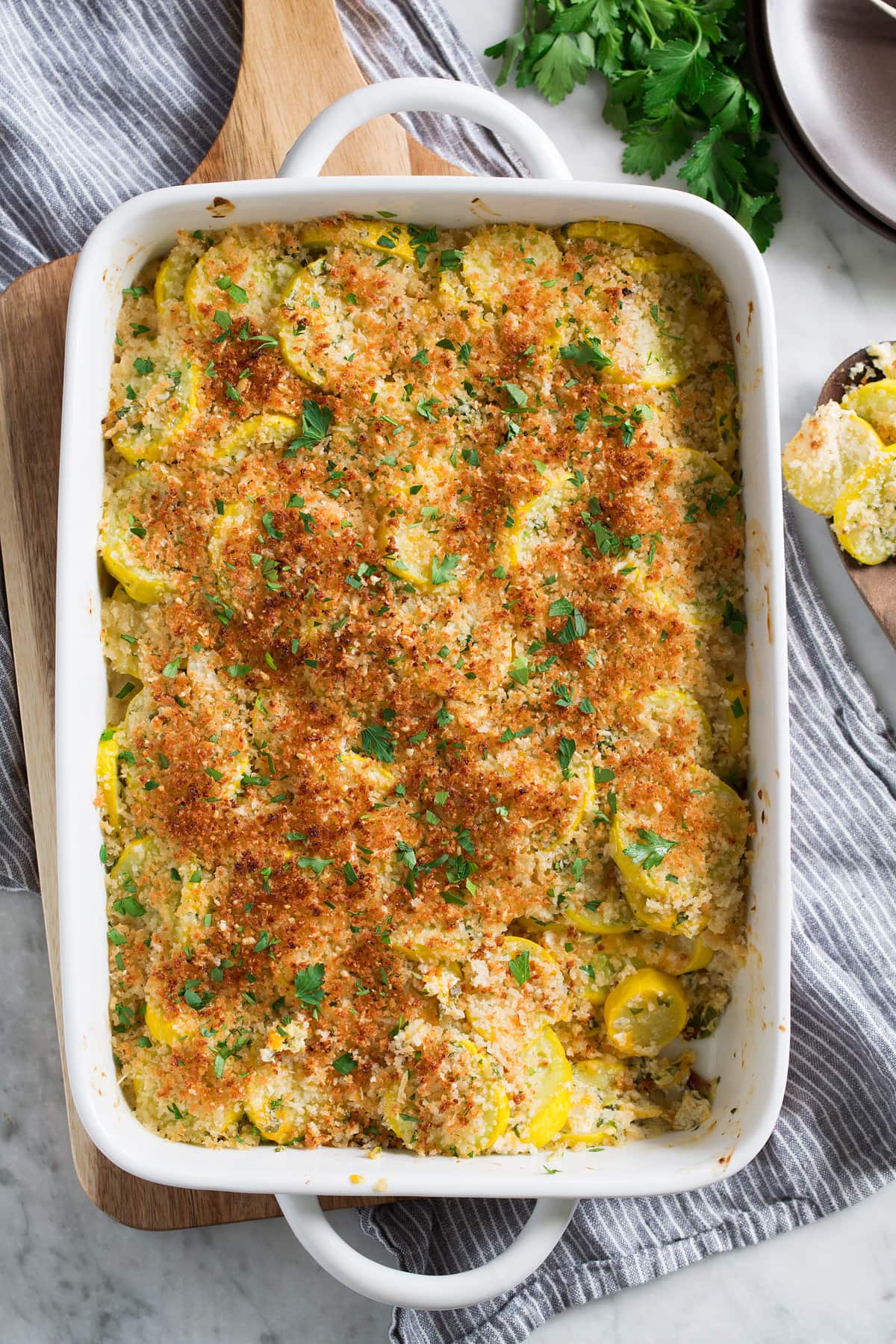 Squash Casserole Yellow squash casserole in a white baking dish with one scoop removed to show filling.