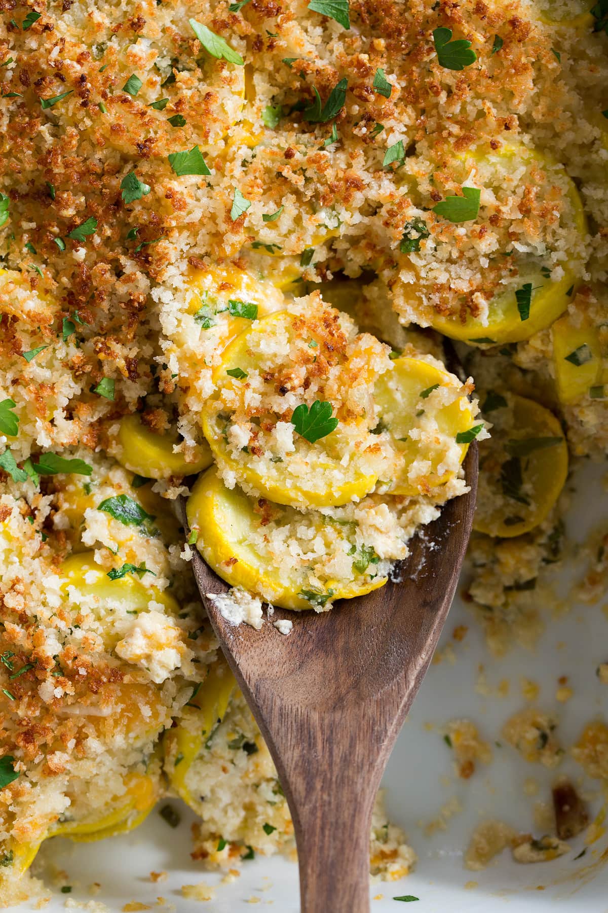 Squash Casserole Close up image of wooden spoon with scoop of squash casserole.