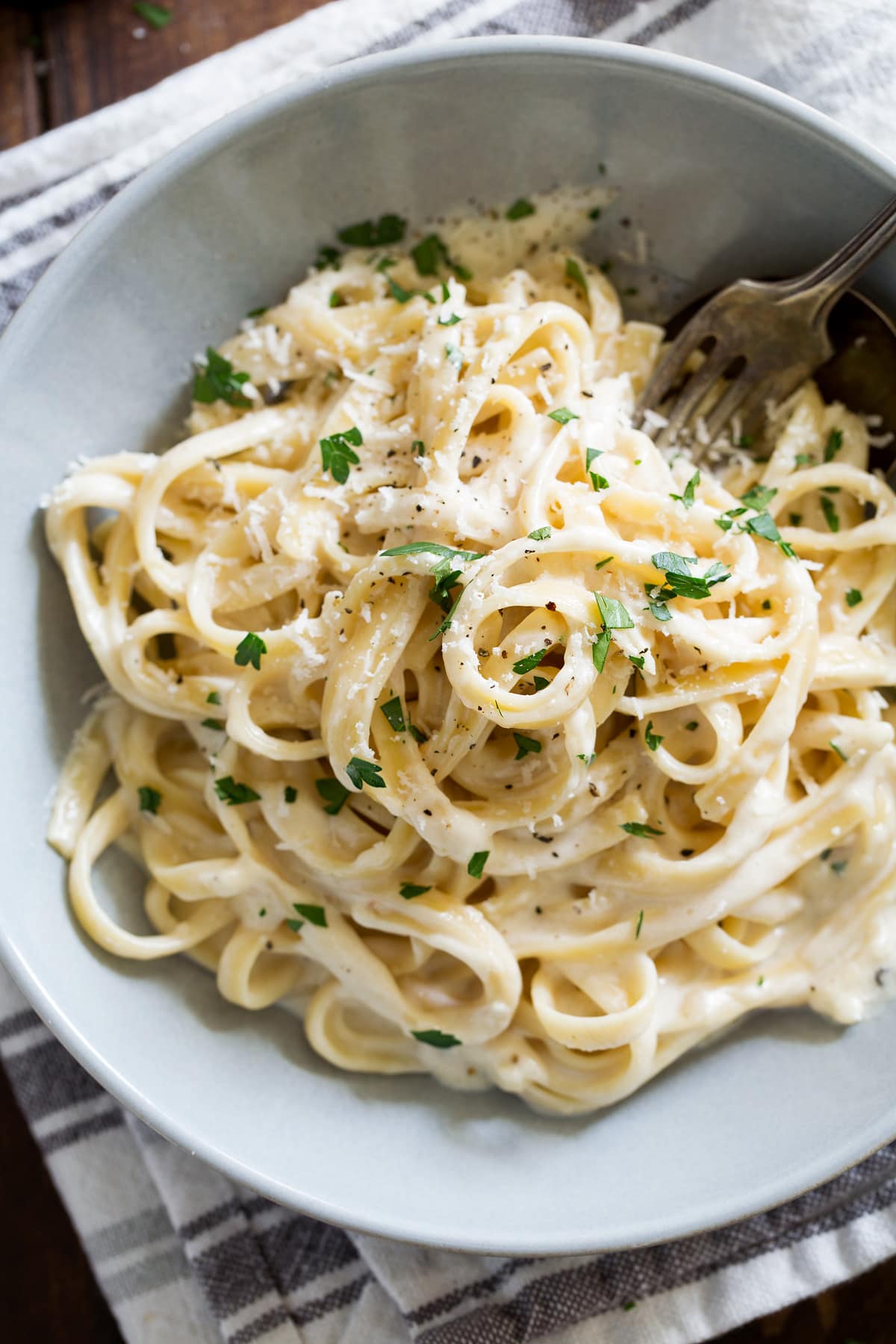 Best Alfredo Sauce - made with half milk and half cream so it's not too heavy, and includes plenty of parmesan for incredible flavor! So easy and seriously delicious! #alfredosauce #alfredo #fettuccinealfredo #dinner #pasta Overhead image of single serving of homemade fettuccine alfredo.