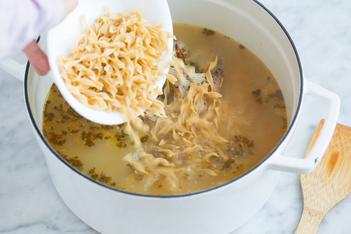 The BEST Quick and Easy Chicken Noodle Soup! This has been my go-to recipe for years. So easy and everyone always loves it! #chickennoodle #soup #dinner #chicken Adding egg noodles to broth mixture in pot.