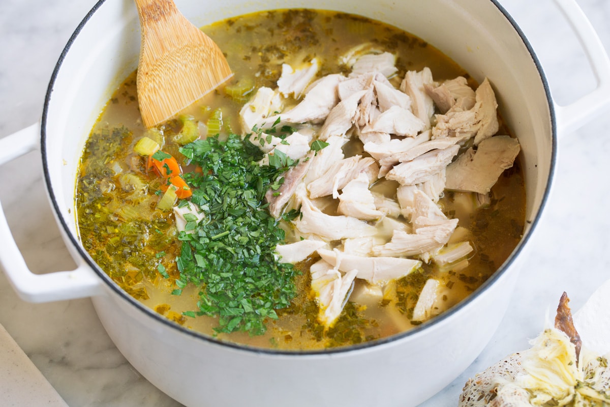 The BEST Quick and Easy Chicken Noodle Soup! This has been my go-to recipe for years. So easy and everyone always loves it! #chickennoodle #soup #dinner #chicken Adding chicken and more fresh herbs to soup.