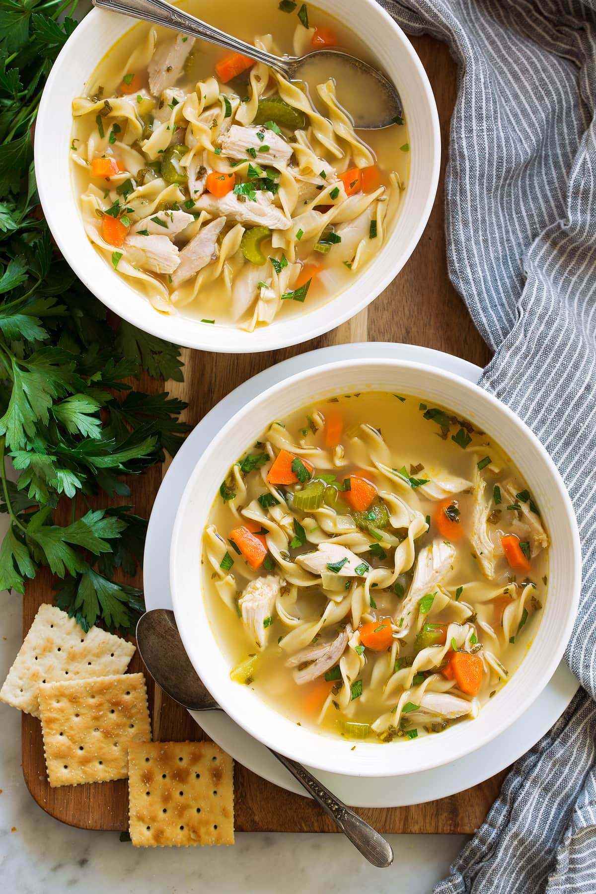 The BEST Quick and Easy Chicken Noodle Soup! This has been my go-to recipe for years. So easy and everyone always loves it! #chickennoodle #soup #dinner #chicken Two servings of the best chicken noodle soup in white bowls.