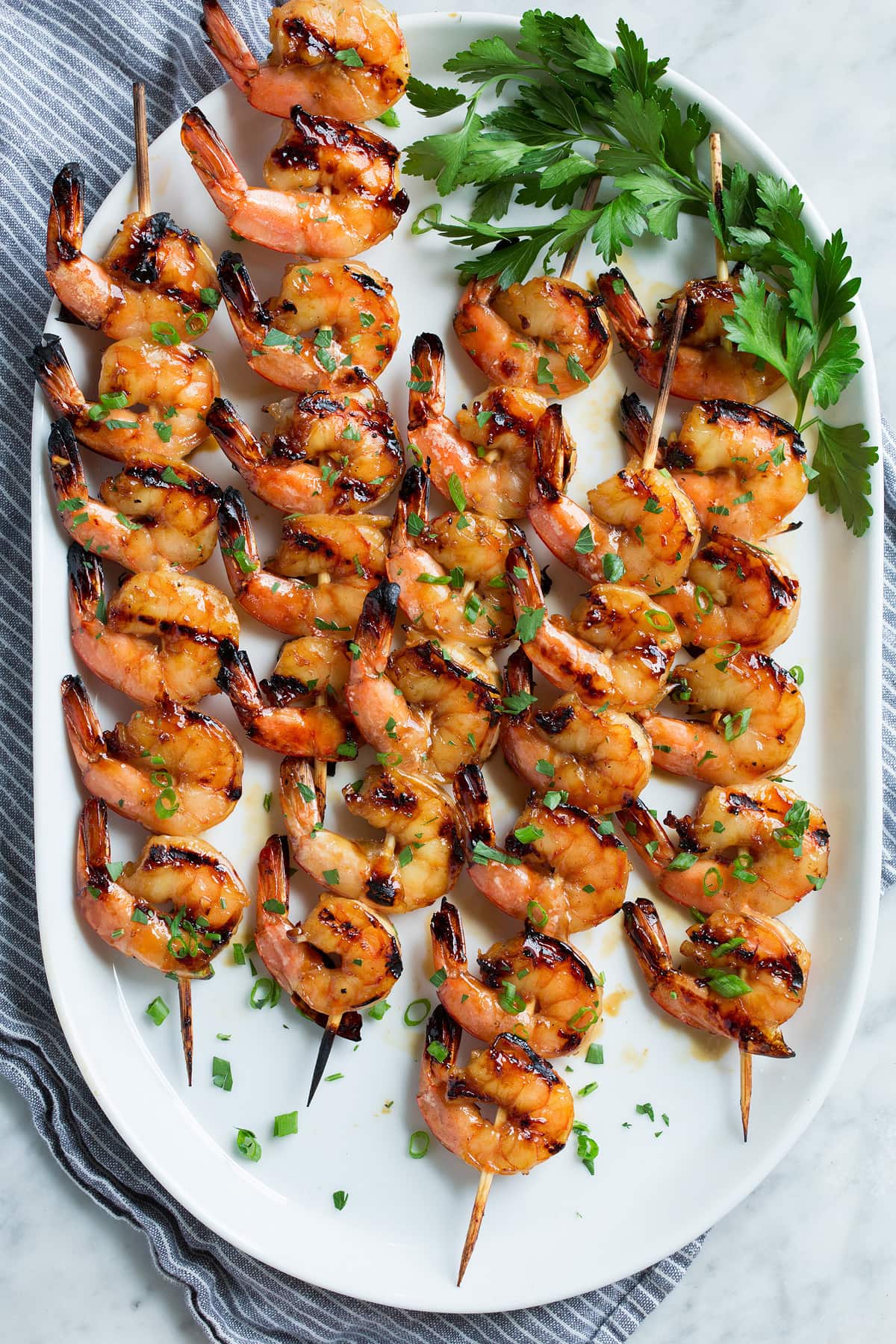 Grilled Shrimp with Honey Garlic Marinade - only 4 ingredients in this fast, easy and flavorful marinade! Perfect for a quick dinner! #shrimp #marinade #grilledshrimp #dinner #recipe Five wooden skewers with grilled shrimp.