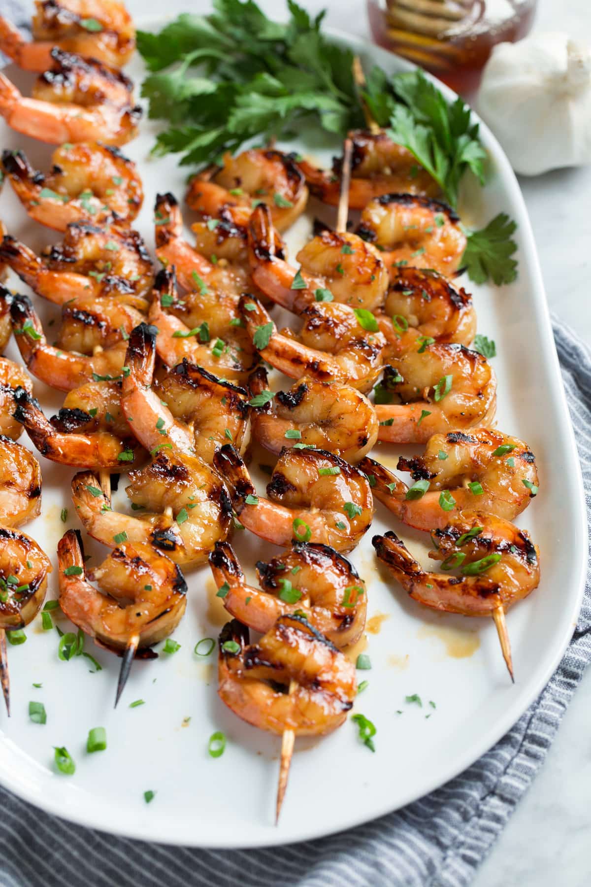 Grilled Shrimp with Honey Garlic Marinade - only 4 ingredients in this fast, easy and flavorful marinade! Perfect for a quick dinner! #shrimp #marinade #grilledshrimp #dinner #recipe Platter with grilled shrimp on skewers