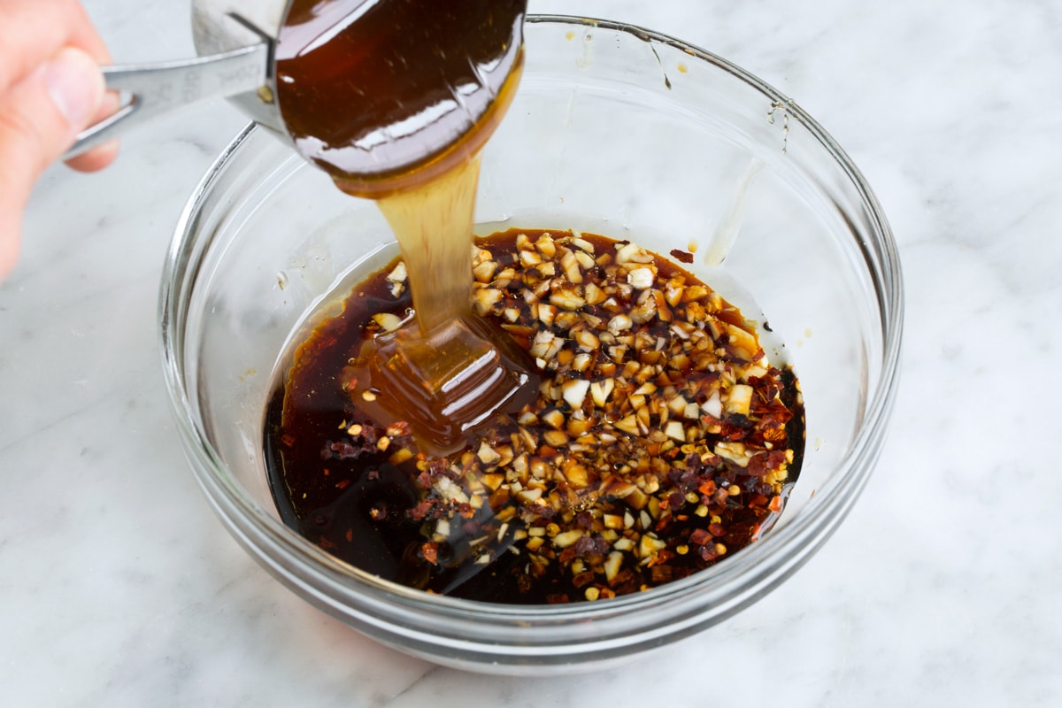 Grilled Shrimp with Honey Garlic Marinade - only 4 ingredients in this fast, easy and flavorful marinade! Perfect for a quick dinner! #shrimp #marinade #grilledshrimp #dinner #recipe Showing how to make shrimp marinade. Mixing soy sauce, garlic, olive oil and honey in a glass mixing bowl.